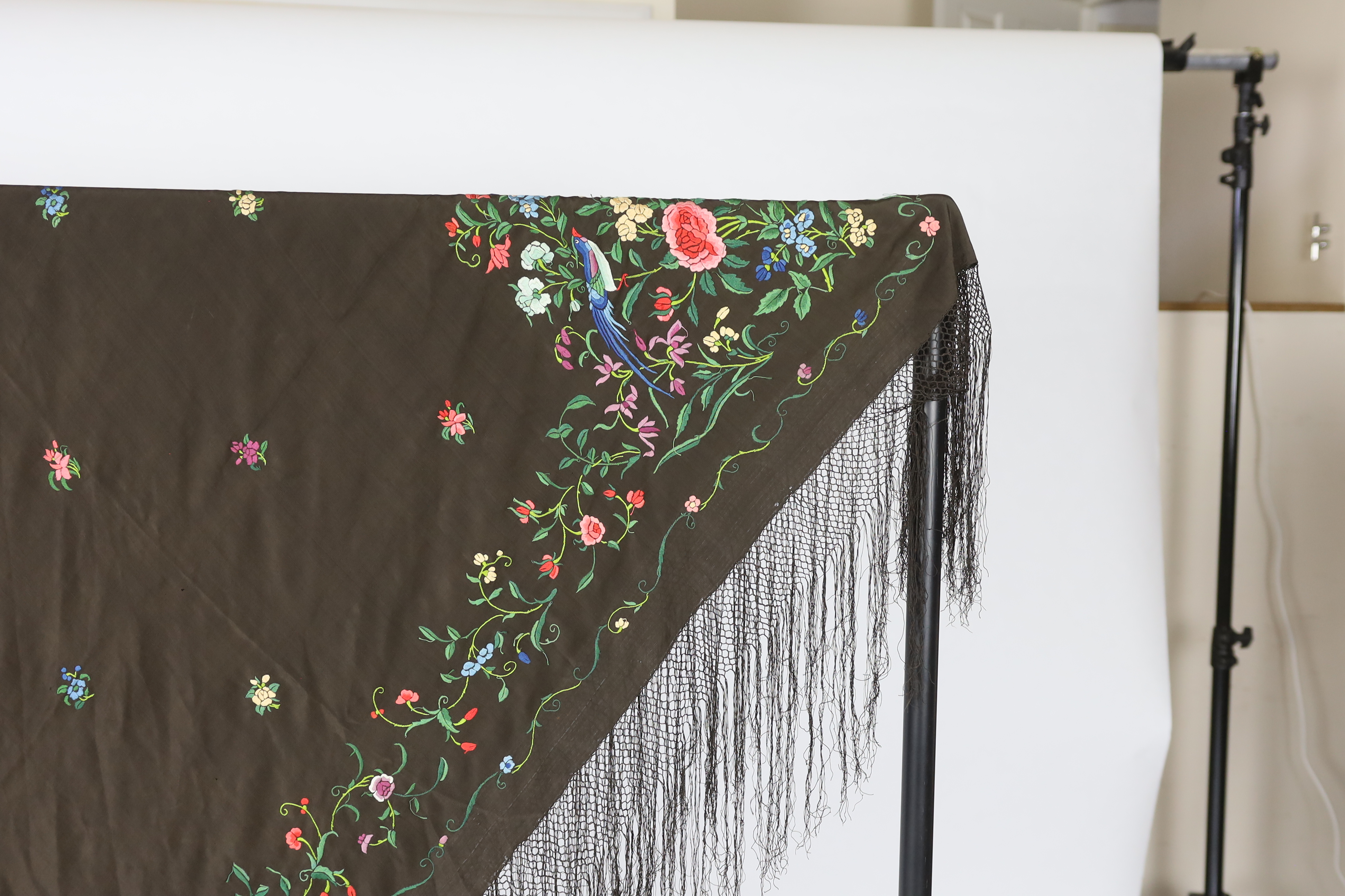 A Chinese silk shawl, circa 1900, embroidered with polychrome threads with birds and flowers against a black silk ground, 164cm sq.